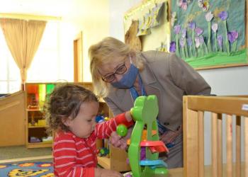 Maine Gov. Janet Mills explores with a pre-schooler one of the educational toys at the Penobscot Bay Area YMCA on May 25. She visited with babies and children before laying out the specifics of the child care investment plan. (Photo by Lynda Clancy)