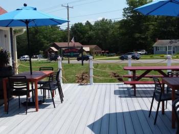 Outdoor seating on a dog-friendly deck. The sign can be seen from Route 1 in Wiscasset. Photo by Kay Stephens