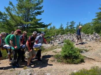 Volunteers from Camden Fire Dept., Camden Hills State Park rangers, Coastal Mountain rescue and North East Mobile Health Services help carry a man up the steep Mount Battie Trail in a Stokes basket after he suffered an ankle injury July 24, approximately half way down the face of Mount Battie. (Photo courtesy Camden Fire Dept.)