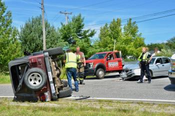 A Camden crash at the intersection of Mechanic Street, where it turns into Hosmer Pond Road, and Melvin Heights Road sent one vehicle onto its side just before noon, Aug. 3. Steve Laite, owner of Camden Exxon, with Camden Firefighter Clint Beveridge and Camden Police Officer Brook Hartshorn tend to scene. (Photos by Lynda Clancy)