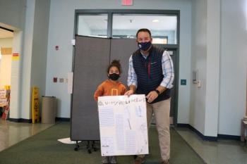 Third Grader Beatrice Mathis of Bonnie Massengale's class, presents her class poster to Rockport Town Manager Jon Duke highlighting the history of quarrying in Camden and Rockport.