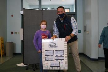Third Grader Elizabeth Fernald, of Danielle McMenimen's class, presents her class poster to Rockport Town Manager Jon Duke highlighting the history of the trains involved in the local quarrying process.