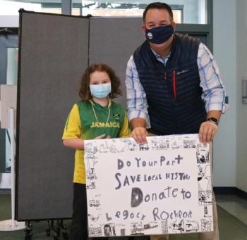 Third Grader Zoe Baker, of Susan Davis' class, presents her class poster to Rockport Town Manager Jon Duke asking the community to donate to Legacy Rockport's latest restoration project.