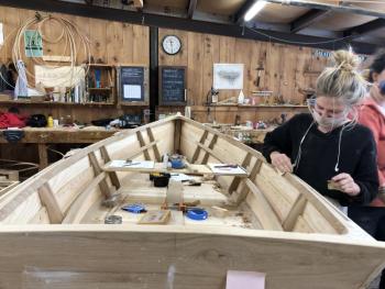 Amber does some final clean up of the interior of the skiff to prepare for oil and paint. (Photo courtesy The Apprenticeshop)