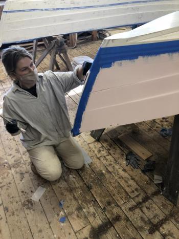 Amber applies topside paint to her skiff in the week leading up to the launch. (Photo courtesy The Apprenticeshop)