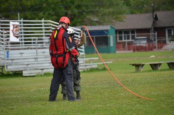 Assistant Fire Chief Andrew Lowe, buckled into a scream suit, waiting with District Forest Ranger Scott Maddox to be lifted by the orange line into the air. (Photo by Lynda Clancy)