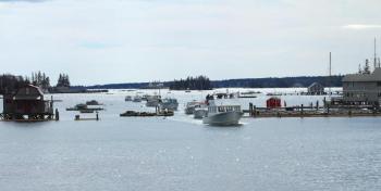 The parade of lobster boats comes through the Boothbay Harbor Footbridge for the very last time. (Photo by Steve Edwards)