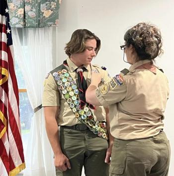 Heidi O'Donnell, a Gold Award Scout and leader and Matthew's mom, pins the Eagle Scout rank on her son. (Photo courtesy Chuck Mahaleris)