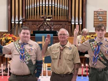 Drew Swindler, Scoutmaster Bruce Bossow, and Josiah Hays make the Scout sign during the ceremony. (Photo courtesy Chuck Mahaleris)