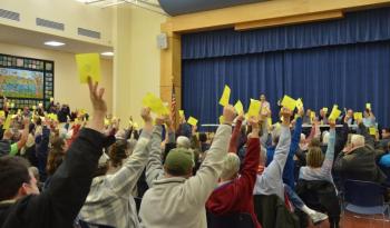 In a call to action following no discussion on the matter at hand Dec. 11, Moderator Andrew Hart asked Lincolnville voters to raise their yellow cards if they approved on a 180-day moratorium on nonresidential developments. The response was swift and unanimous in favor of the moratorium. (Photo by Lynda Clancy)