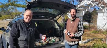 Aaron Englander helps volunteer Michael Leonard load his vehicle with jars of maple syrup to donate to Come Spring Food Pantry. (Photo courtesy MCHT)