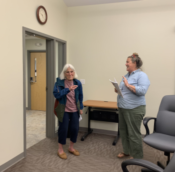 Lincolnville Select Board Chair Ladleah Dunn (right) surprises Corelyn Senn with the first copy out of the box of the 2024 Lincolnville Town Report. (Photo by Lynda Clancy)