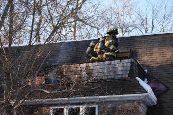 Camden firefighters cut and saturate around a chimney pipe at 201 Chestnut Street, in Camden, Feb. 11, 2025. (Photo by Sarah Thompson)