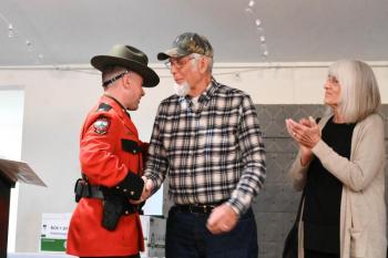 Legendary Maine Game Warden Dennis McIntosh (center) is congratulated by Lt. Aaron Cross and his wife, Carmen.