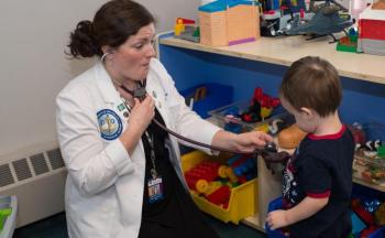a medical student uses a stethoscope on a young boy.