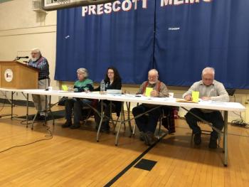 three men and two women sit at a table officiating a meeting