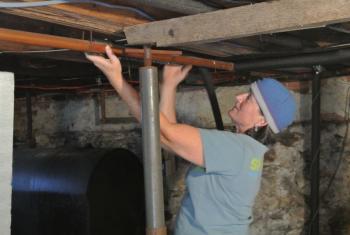 Wrapping pipes to insulate, improves efficiency for the older housing stock. (Photo courtesy Midcoast Habitat for Humanity)