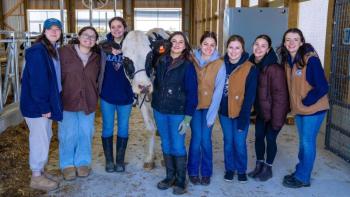 Several University of Maine students and Dancer the cow pose for a photo during the grand opening ceremony of the new robotic milking barn Witter Farm. (Photo courtesy University of Maine)