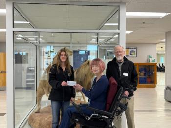 Belfast Peer Leadership LEO vice-president Story Carlson presents the check to the But Still I am One directors in the Belfast Area High School lobby. (Photo courtesy Charles Lagerbom)