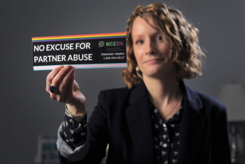 regina rooney holds a bumper sticker that reads no excuse for partner abuse