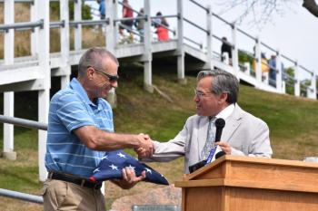 Bob Trapani, Jr, holds a U.S. flag that once flew above the U.S. Capitol. The flag is presented by Chuck Mahaleris, State Office Representative for U.S. Senator Susan Collins. (Photo by Sarah Thompson)