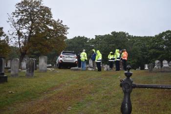 Car in cemetery as seen from driveway gate