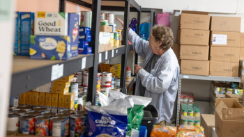 A woman reaches for an item on a shelf.