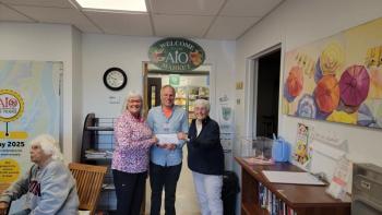Diane Zollo and Faith Vautour, from Goose River Golf Club's Ladies League, present AIO food pantry CEO Alan Kearl with $1200.