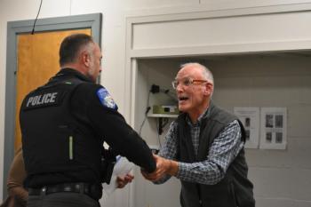Patrol Officer Chris Hansen shakes hands with Select Board Chair Chris Rector. (Photo by Sarah Thompson)