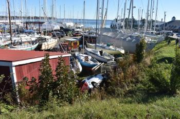 Vehicle on its side at the foreground of a boatyard
