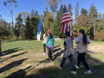 Girl Scouts carry flags during a ceremony