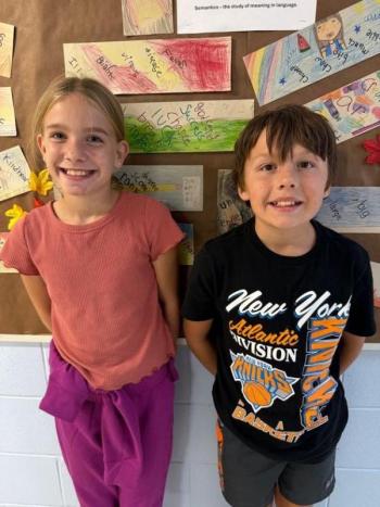 Girl and boy pose for picture as assembly emcees