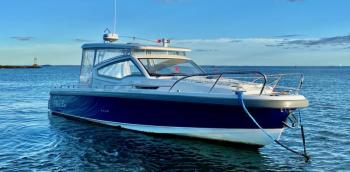 A well-equipped Nimbus W9 buttoned up against the Maine weather with full side curtains and an electrically powered sunroof. The mooring bridle takes advantage of both cleats on the bow. The electric anchor windlass can be operated with a remote control from anywhere on the boat; the remote also can run the bow thruster. The touches of orange are wind vanes on accessory whirligigs meant to deter gulls and cormorants. A well-equipped Nimbus W9 buttoned up against the Maine weather with full side curtains and an electrically powered sunroof. The mooring bridle takes advantage of both cleats on the bow. The electric anchor windlass can be operated with a remote control from anywhere on the boat; the remote also can run the bow thruster. The touches of orange are wind vanes on accessory whirligigs meant to deter gulls and cormorants.