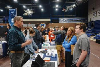 (Photo courtesy Southern Maine Community College) Information fair setup with visitors on one side of a table listening to exhibitors