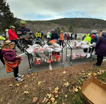 Bicyclers stand around carts filled with frozen turkeys