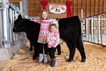 Two girls pose in front of Belted Galloway cow