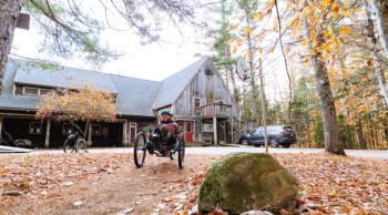 Woman rides an adaptive mountain bike away from a building
