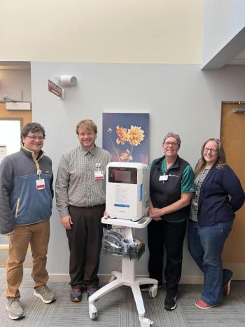 Four people stand around a portable machine