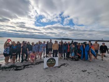 Large crowd of participants pose for a picture on the beach