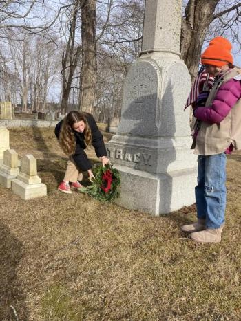 Two females place a wreath