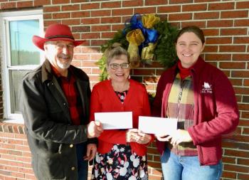 One male and two females pose with two checks