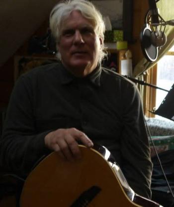 Philip Austin seated holding guitar