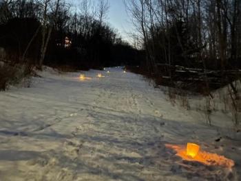 snow-covered trail with luminaries along the path