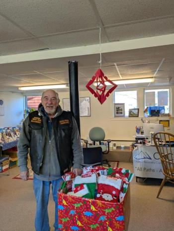 Robert "Biker Bob" Sheehan standing before The Devils Pride Motorcycle Club's donation of Christmas stockings to the Coastal Recovery Community Center located in Rockland. Photo courtesy Bob Sheehan