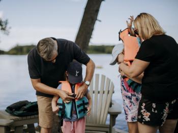 Adults helping children into life jackets