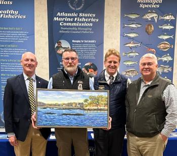 Award winner holds a painting as he and three other men pose for picture