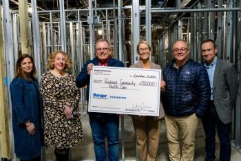 Six adults pose with oversized donation check