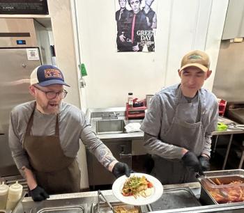 Ryan Tinker and Crispin Goodnow, in the Camden Hills Regional High School kitchen Jan. 28, serving up Graffam Seafood's Maine Coiast Founder Fishcake with a topping of Wakame Slaw. (Photo by Lynda Clancy)