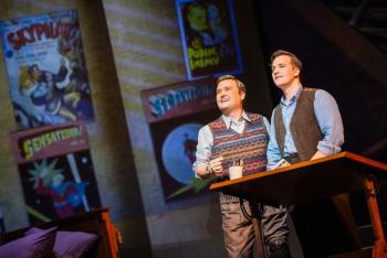 Two men stare off into the distance in front of comic book covers