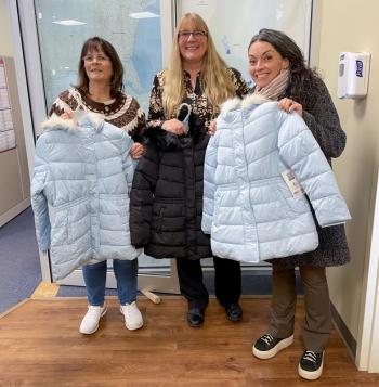 Three women pose with winter coats